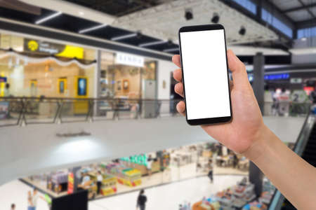 human hand hold  smartphone, tablet, cell phone with blank screen on blurry floor of department store. Concepts of social capital.の写真素材