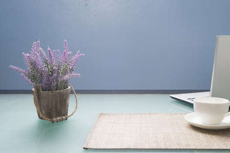 Glasses office table with white cup of coffee, laptop and purple lavender flower on pot, Concept of office life and mock up free space for advertisement.の写真素材