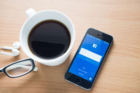 CHONBURI- November 18 : Wood table with coffee cup and facebook application on cell phone, Concept of Coffee break  in Thailand on November 18, 2016 in Chonburi, Thailand.のeditorial素材