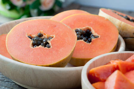 kitchen table with sliced of fresh papaya fruit on wood plate. concept of sliced tropical fruit for lose weight and healthcare.  selective focus on top view.の写真素材