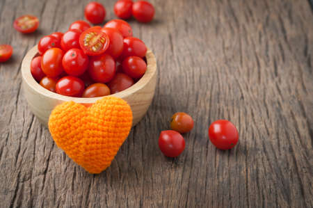 kitchen table with dwarf tomatoes on wood plate with orange heart shape. healthy eating and dieting food, concept of health care, Image focus top view.の写真素材