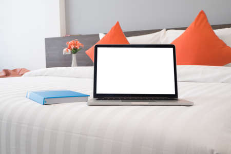 the bed with blank screen laptop, book,  beautiful flower at bedroom. side view on bed. front view notebook.の写真素材
