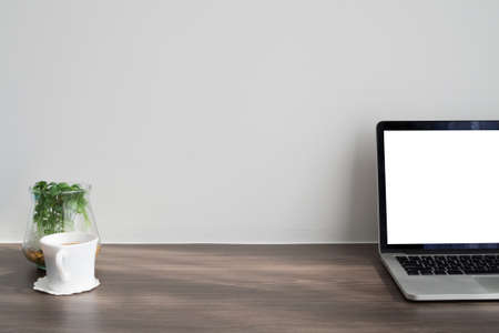 Office desk with blank screen on laptop, fresh coffee cup, dwarf tree on glass vase and cement wall background. concept of business lifestyle.の写真素材