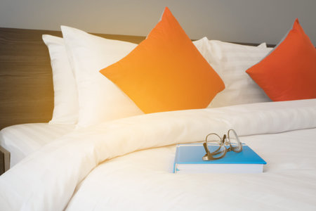 white bed with modern glasses on blue book at bed room.