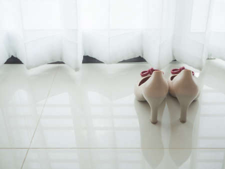 woman casual shoes put on tile floor with beautiful white drape window texture background at living room.の写真素材