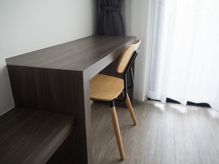 wooden office table with modern chair and blurry beautiful white drape window texture background at...