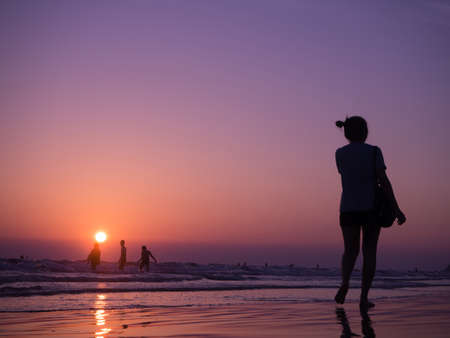 silhouette shadow of young asian woman walking on beach with sunset. concept of holiday beach.の写真素材