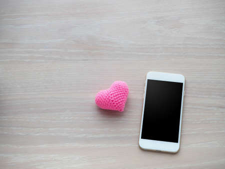 wood office table with blank screen on smartphone, tablet, cell phone for text and pink heart shape sign. view from top view office table.の写真素材