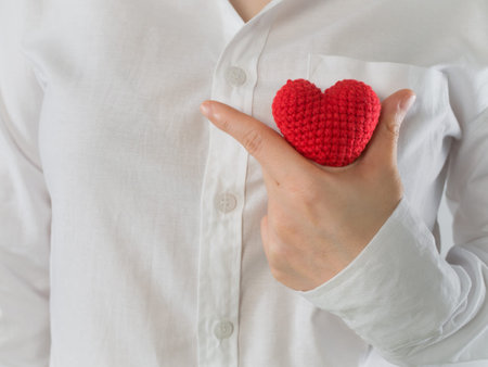 close up of woman in white shirt  holding red shape sing on isolated background, concept of health...