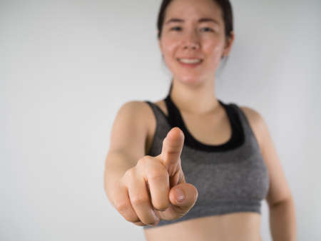 Smiling face of Young Asian woman in sport bra pointing finger on isolated background.の写真素材