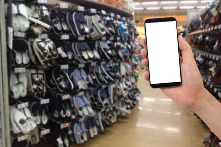 human hand hold blank screen smartphone, tablet, cell phone on shoes shelf. concept of shopping online.の写真素材