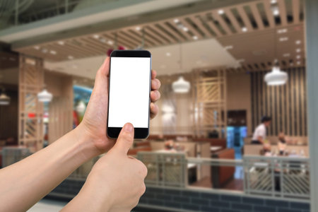 human hand hold and scanning fingerprint on smartphone, tablet, cell phone with blurry dining room...
