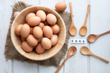 kitchen table with raw eggs set on wood basket and eggs text letter.