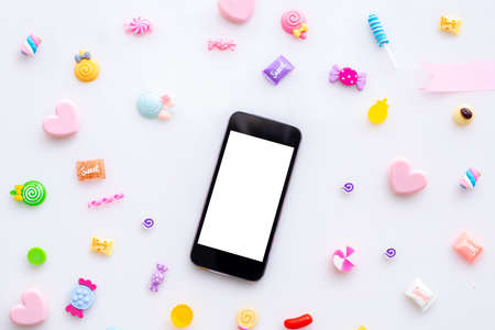 blank screen on smartphone cell phone, tablet with sweet candy on white background, valentines day background, top view.0の写真素材
