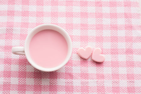 cup of milk and heart shape on pink tablecloth, Valentine's day background, top view.