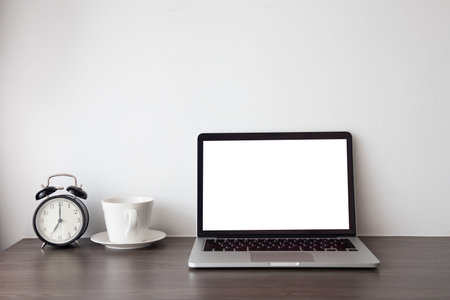 wood office table with blank screen on laptop, notebook and hot coffee cup.