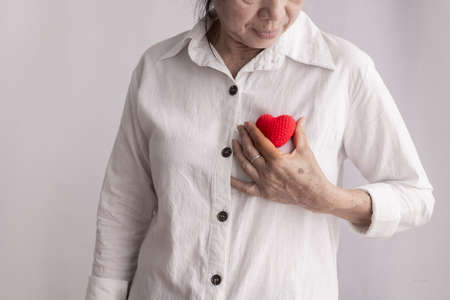 smiling asian elderly woman holding red heart shape, concept of prevention heart disease, front view.の写真素材