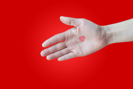 human hand hold handshake with red heart shape sign on isolated red background, copy space.