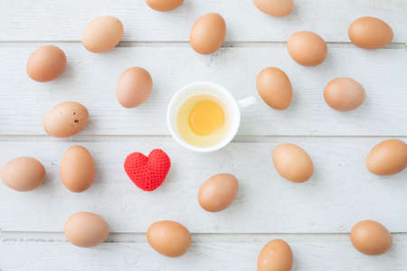white kitchen table texture background with fresh eggs set , yellow yolk eggs and red heart shape sign, view from top table.の写真素材