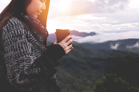 young asian woman drinking hot coffee on scenery view in morning.