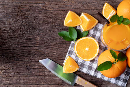 Wood table with fresh orange fruit and glass of orange juice, view from above table.の写真素材