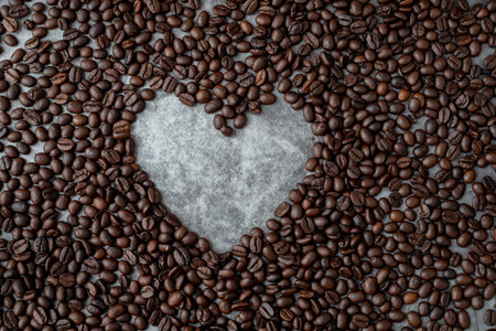 coffee beans with heart shape sign on dark wall texture background, view from above table.