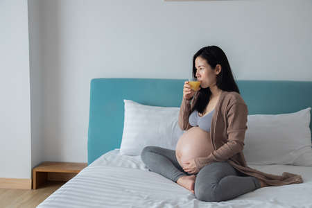 pregnancy, motherhood and expectation concept - happy pregnant woman drink orange juice.の写真素材