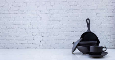 Black kitchenware on white brick wall texture background, view from front table.の写真素材