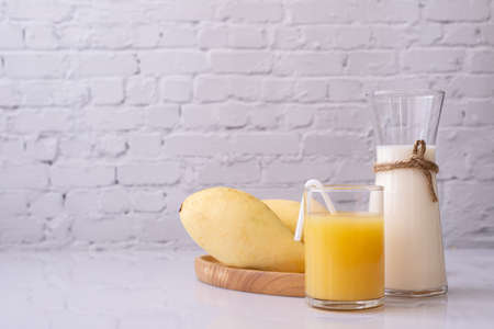 Glass of Mangoes juice and bottle of milk on kitchen table. Front view.の写真素材
