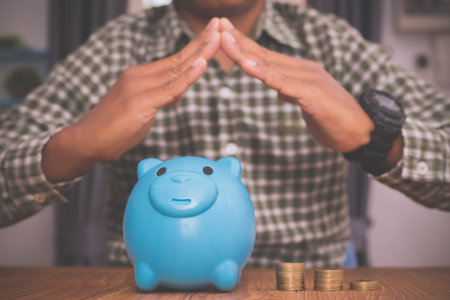 Businessman holding hand home sign on piggy bank.