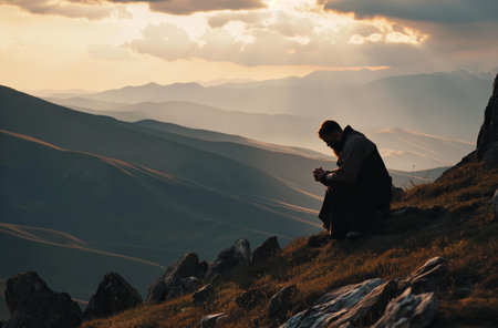 Solitary prayer at mountain sunsetの素材