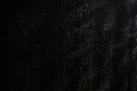 Abstract close-up of a dark fabric texture with intricate patterns and subtle lighting