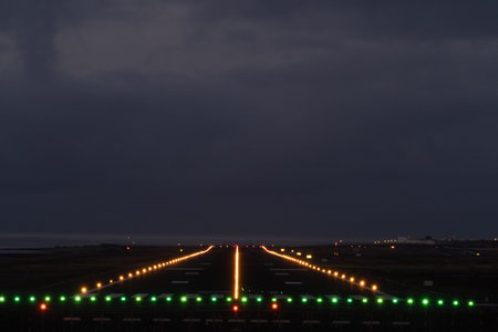 Empty airport runway at night, bathed in green and orange lights, guiding planes for safe takeoff...