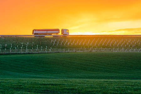 Truck passing sunrise in a rural green belt areaの写真素材