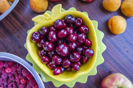 Ripe cherries peeled from twigs in a fruit bowl on the tableの写真素材