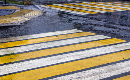 The marking of a pedestrian crossing on the road is covered with water during rainの写真素材