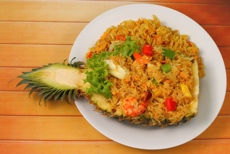 seafood and baked rice in pineapple on a wood tableの写真素材