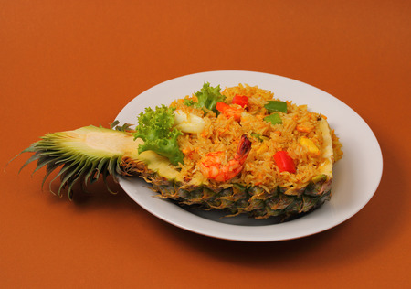 seafood and baked rice in pineapple with a brown backgroundの写真素材
