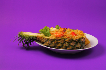 seafood and baked rice in pineapple with a purple backgroundの写真素材