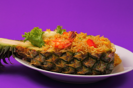 seafood and baked rice in pineapple with a purple backgroundの写真素材