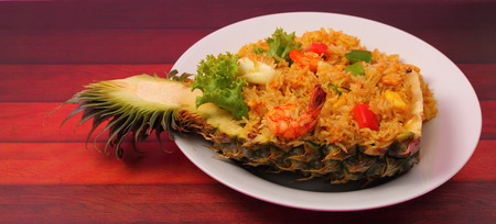 seafood and baked rice in pineapple on a wood tableの写真素材