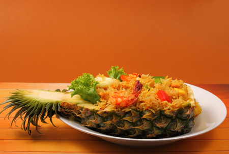 seafood and baked rice in pineapple with a brown background on a wood tableの写真素材