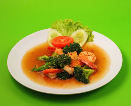 Shrimp and broccoli stir fry in sauce with a green backgroundの写真素材