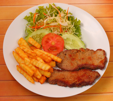 Grilled beef and french fries thai style on a wood table topの写真素材