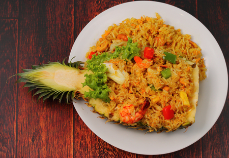 seafood and baked rice in pineapple on a wood tableの写真素材