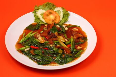 Thai style Crispy pork stir fry on an orange backgroundの写真素材