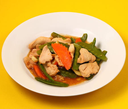 chicken stir fry thai style on a yellow backgroundの写真素材