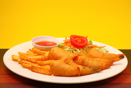 deep fried prawns with salad and chilli with a yellow background on wood table topの写真素材