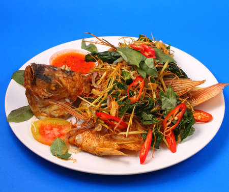 thai style fried fish with herbs on a blue backgroundの写真素材
