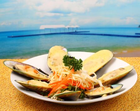 new Zealand mussels in cheese sauce on a wood table top on the beachの写真素材